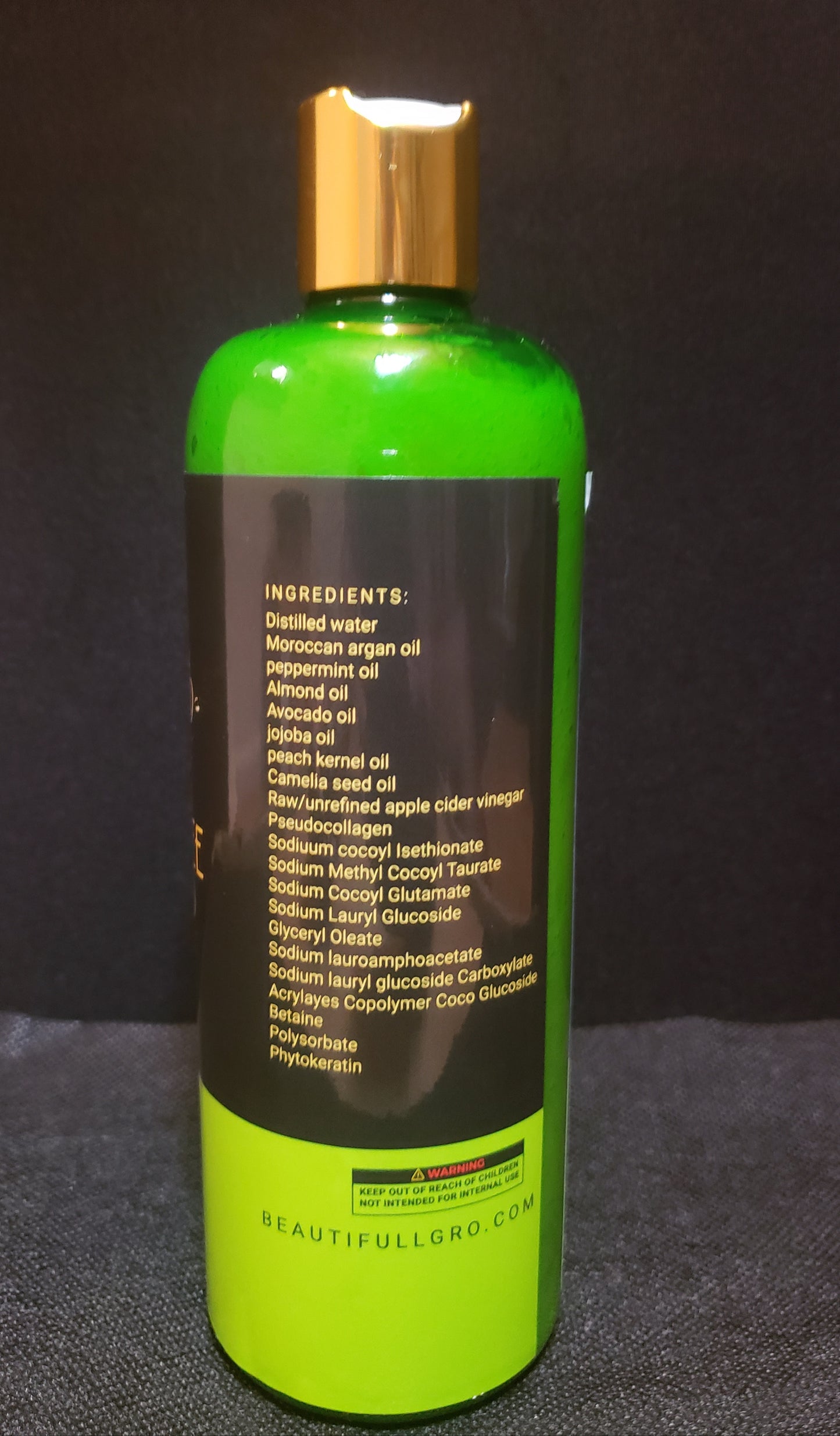 Bottle with green label and gold cap on a dark background